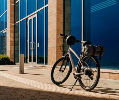 Modernes Pendler-/E-Bike als Dienstrad vor einem Bürogebäude, mit Helm am Lenker und Packtasche