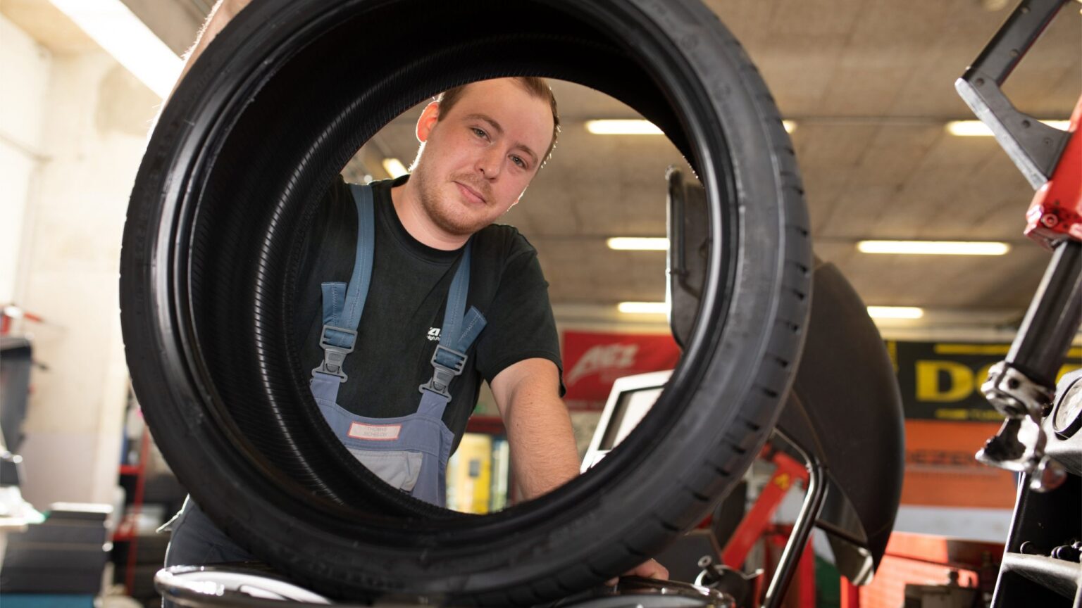 Mitarbeiter von Weichberger montiert in der Werkstätte einen Autoreifen – Reifen St. Pölten